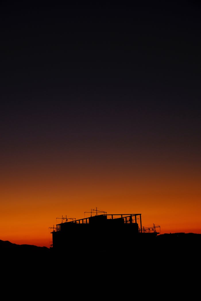 Silhouette of a construction site against a stunning sunset sky with vibrant colors.